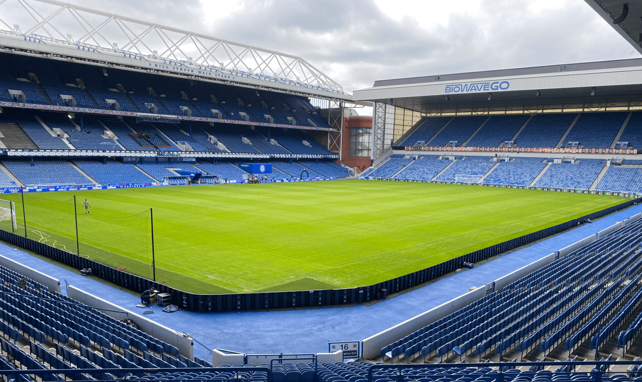 View across the grass pitch and blue seating at Rangers stadium