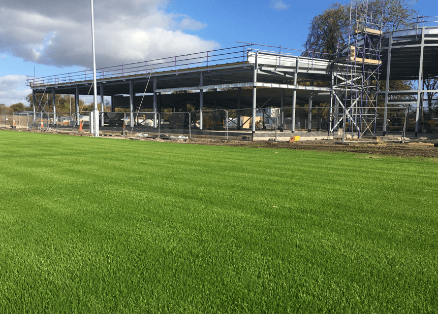 Natural-turf training pitch beside a building under construction