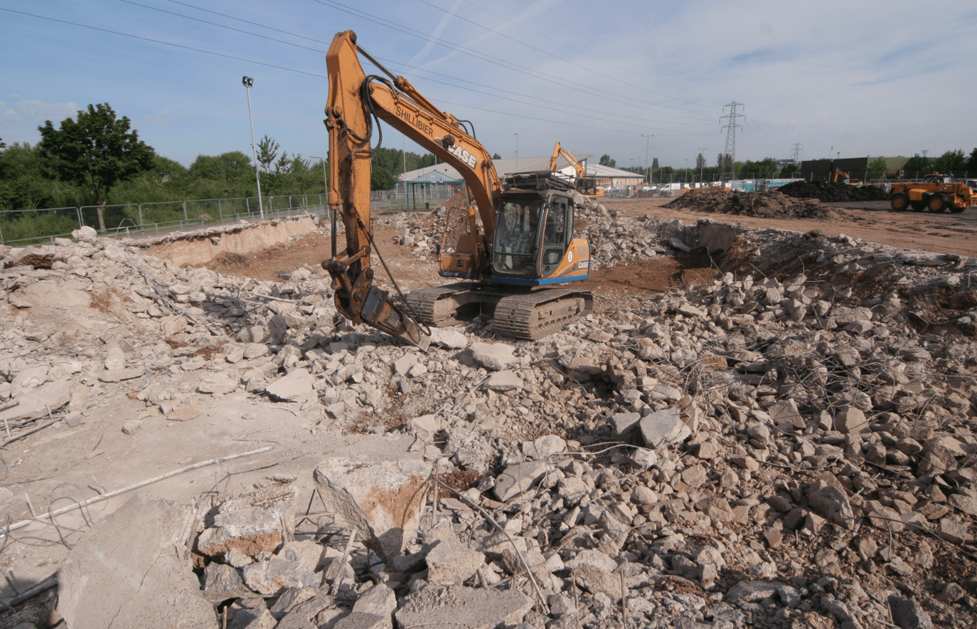 Excavator working among exposed ground and construction material