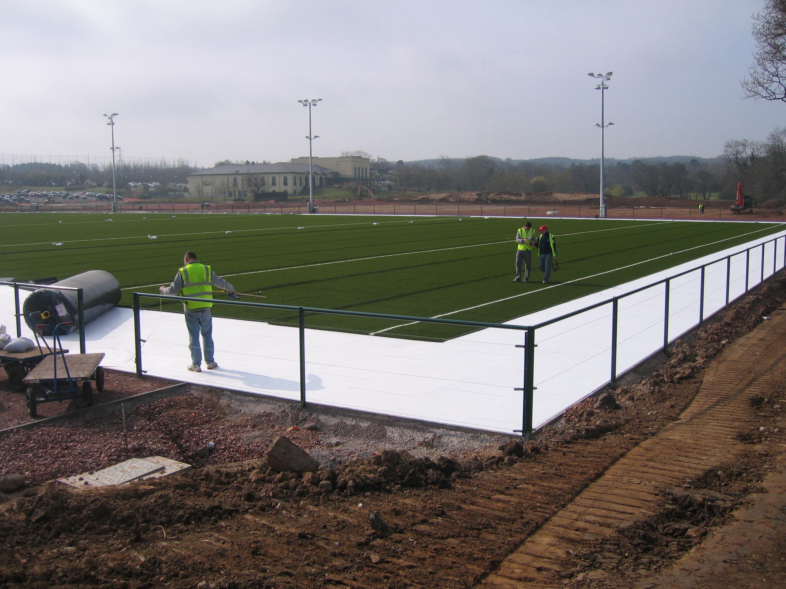 Synthetic rugby pitch with goalposts and surrounding fencing