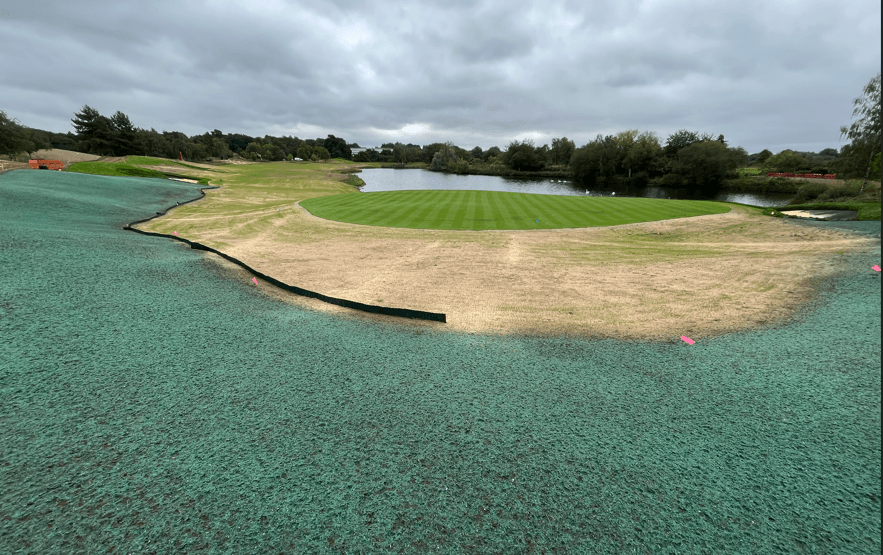 Renovated golf green beside water, with surrounding ground under establishment